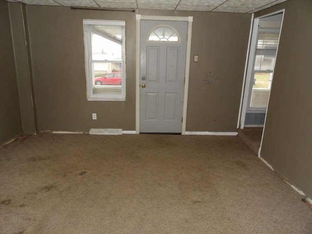 foyer entrance with a paneled ceiling, a wealth of natural light, and carpet floors