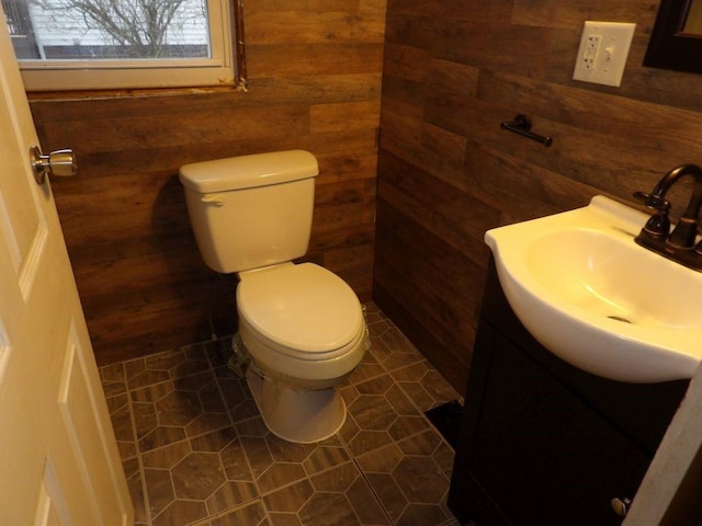 bathroom featuring vanity, wood walls, and toilet