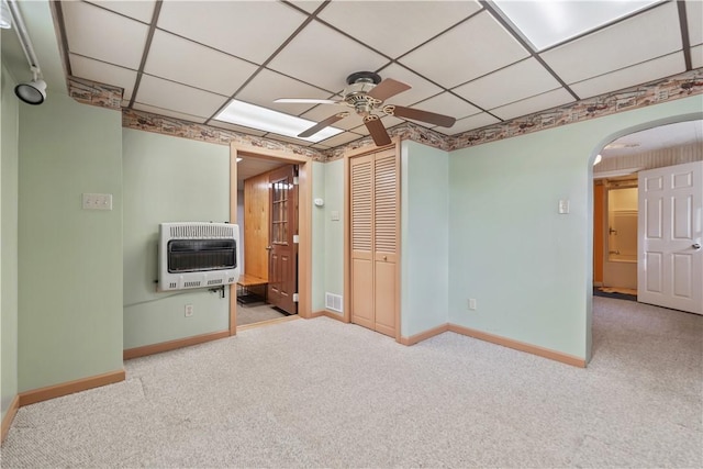 interior space with heating unit, a paneled ceiling, and light colored carpet