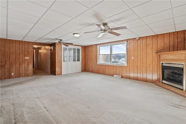 unfurnished living room featuring carpet, ceiling fan, and wood walls