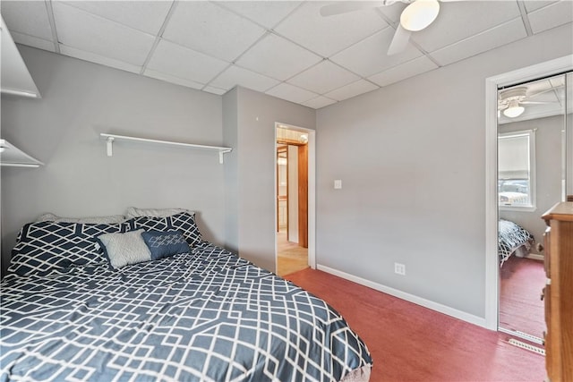 carpeted bedroom with a paneled ceiling and ceiling fan