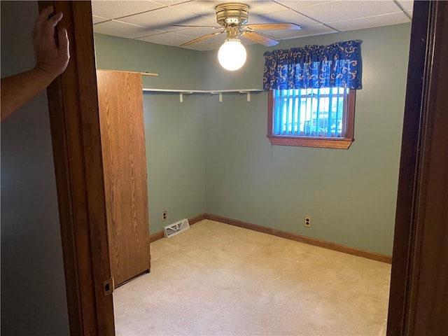 carpeted empty room with a drop ceiling and ceiling fan