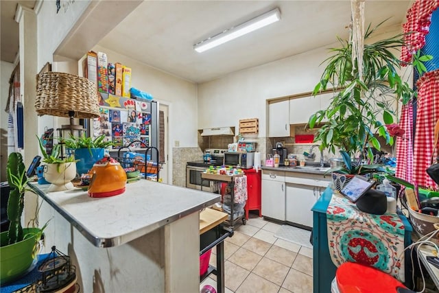 kitchen featuring premium range hood, sink, light tile patterned flooring, white cabinetry, and stainless steel appliances