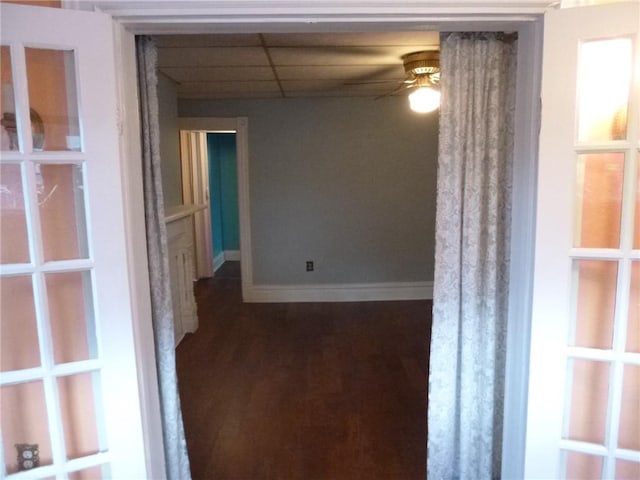 empty room with a paneled ceiling, ceiling fan, and dark hardwood / wood-style flooring