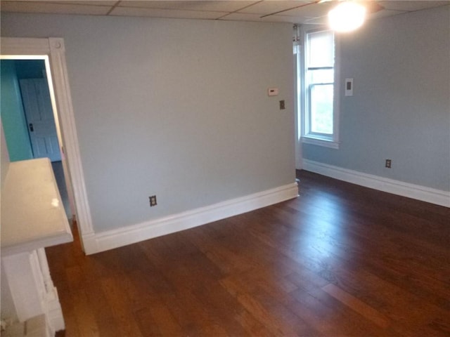 spare room featuring dark hardwood / wood-style floors and a drop ceiling