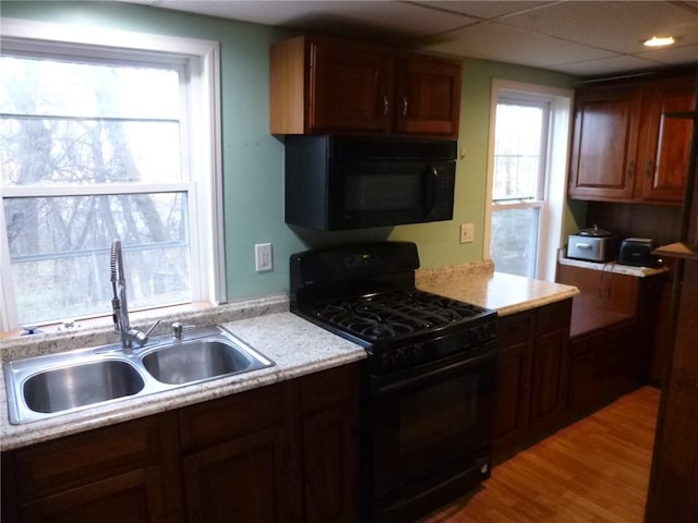 kitchen with black appliances, a healthy amount of sunlight, light wood-type flooring, and sink