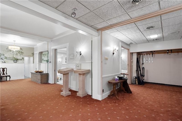 interior space with a paneled ceiling, carpet floors, and crown molding