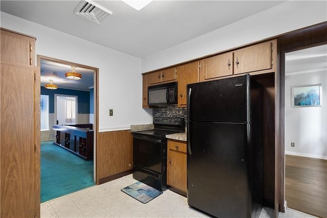 kitchen with black appliances, light colored carpet, and backsplash