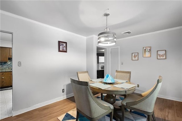 dining area with hardwood / wood-style floors and ornamental molding