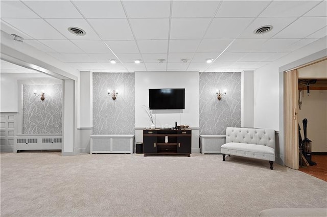 carpeted living room featuring radiator and a drop ceiling