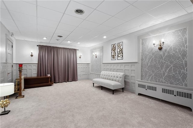 living area with carpet flooring, a drop ceiling, and radiator