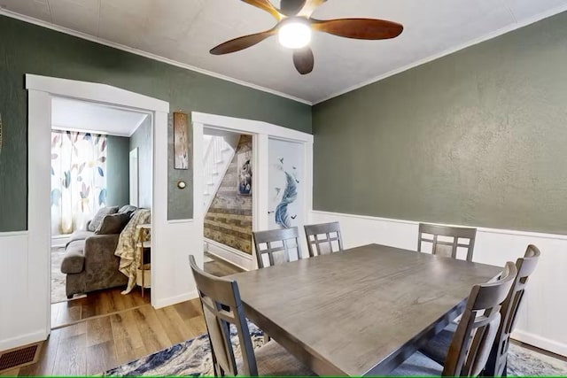 dining room with hardwood / wood-style flooring, ceiling fan, and crown molding