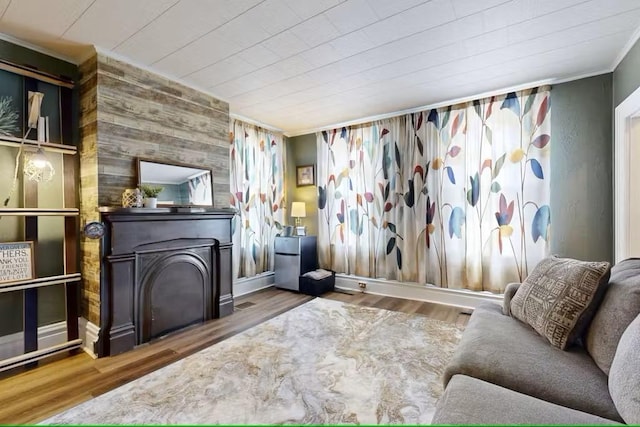 living room featuring hardwood / wood-style floors, a wood stove, crown molding, and wood walls