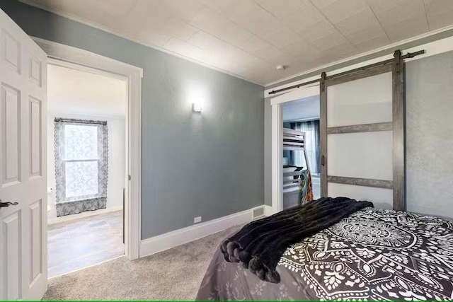 bedroom featuring a barn door, light colored carpet, and crown molding