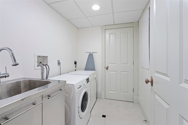 laundry room featuring cabinets, light tile patterned floors, washing machine and dryer, and sink