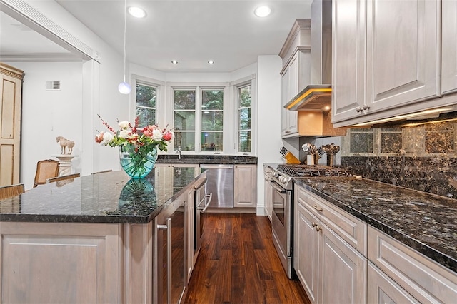 kitchen with stainless steel appliances, wall chimney range hood, dark hardwood / wood-style flooring, pendant lighting, and a kitchen island