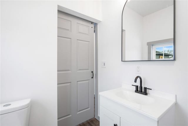 bathroom with hardwood / wood-style flooring, vanity, and toilet