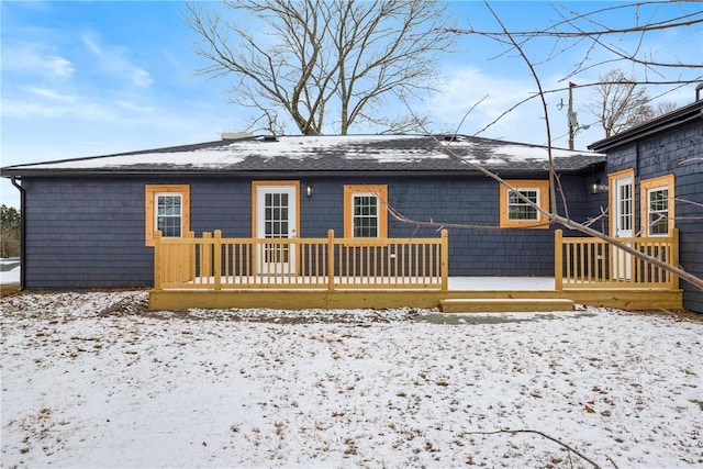 snow covered back of property with a wooden deck