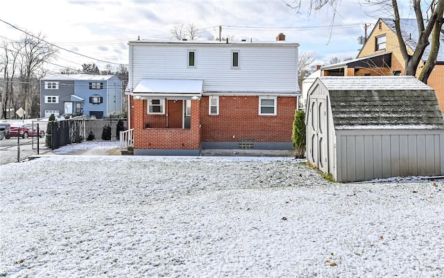 snow covered rear of property with a storage unit