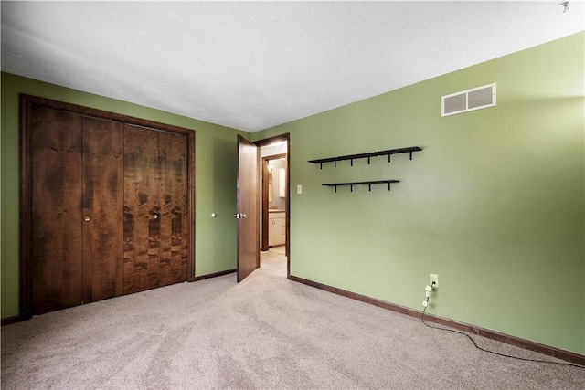 unfurnished bedroom with a closet and light colored carpet