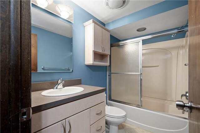 full bathroom with shower / bath combination with glass door, vanity, tile patterned floors, and toilet