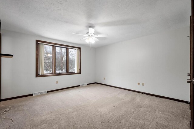 carpeted empty room with ceiling fan and a textured ceiling