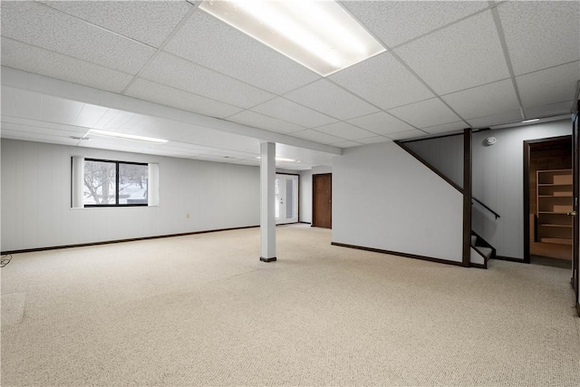 basement with a paneled ceiling and light carpet