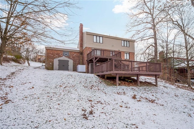 snow covered house featuring a deck and a storage shed