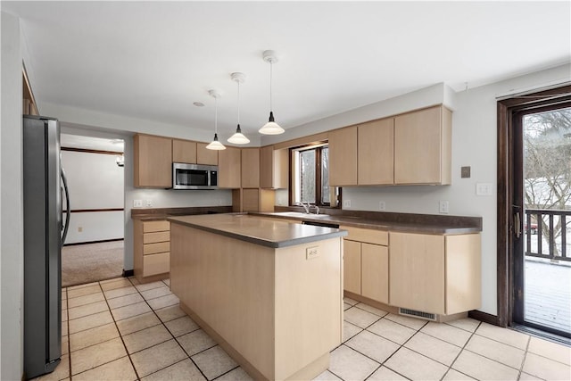 kitchen with a center island, stainless steel appliances, decorative light fixtures, and light brown cabinets