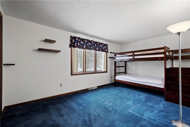 unfurnished bedroom with a textured ceiling and dark carpet