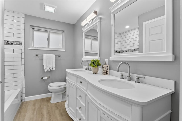 full bathroom featuring hardwood / wood-style flooring, vanity, toilet, and tiled shower / bath