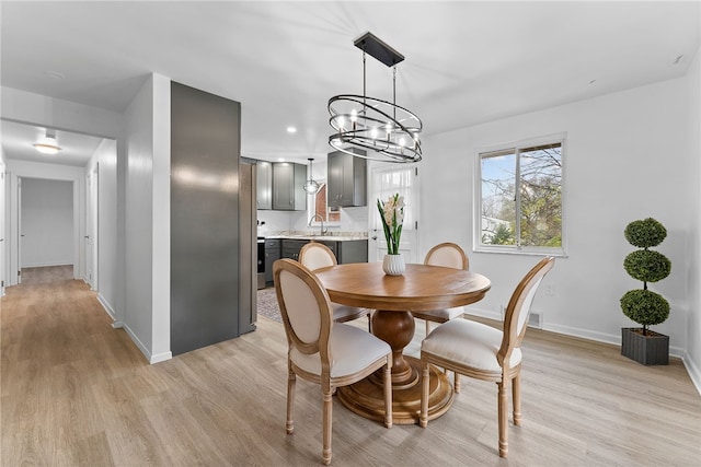 dining space with a chandelier, light wood-type flooring, and sink