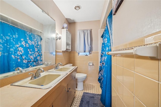 bathroom featuring tile patterned flooring, vanity, toilet, and tile walls