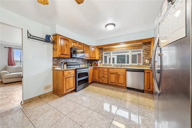 kitchen featuring decorative backsplash, sink, light tile patterned floors, and appliances with stainless steel finishes