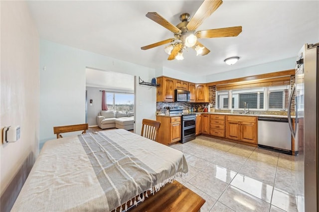 kitchen featuring sink, ceiling fan, appliances with stainless steel finishes, tasteful backsplash, and light tile patterned flooring