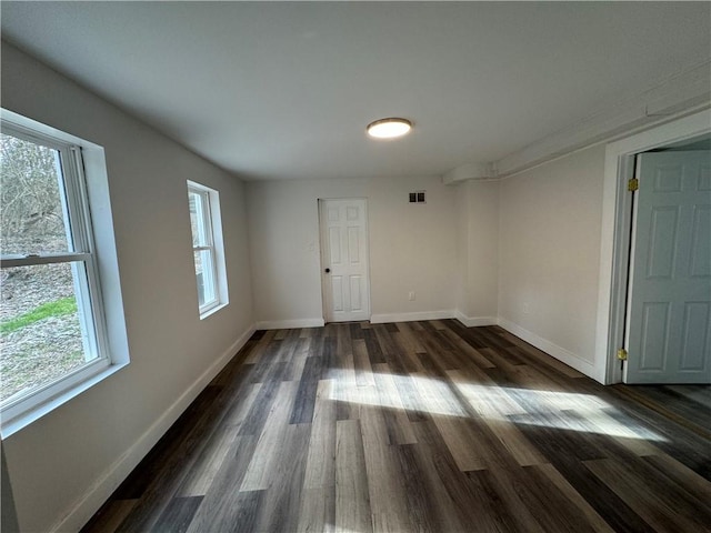 unfurnished room featuring a wealth of natural light and dark wood-type flooring