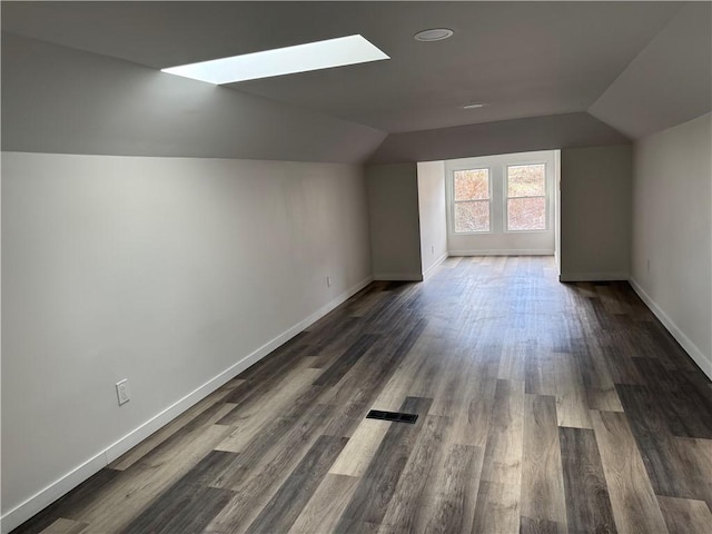 additional living space with dark hardwood / wood-style flooring and lofted ceiling with skylight