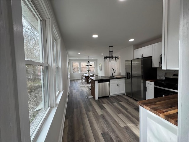 kitchen featuring sink, decorative light fixtures, dark hardwood / wood-style flooring, white cabinetry, and stainless steel appliances