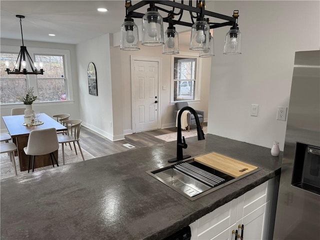 kitchen featuring white cabinetry, sink, dark wood-type flooring, stainless steel fridge, and a chandelier