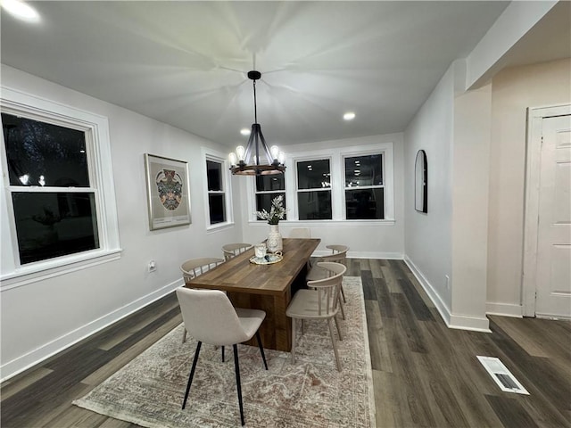 dining space featuring dark wood-type flooring and an inviting chandelier