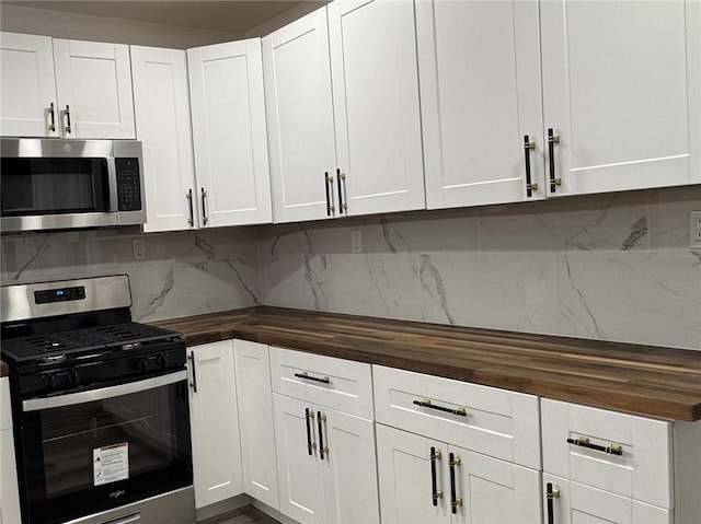 kitchen featuring butcher block countertops, decorative backsplash, white cabinets, and appliances with stainless steel finishes