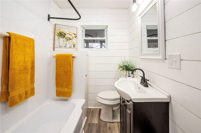 full bathroom featuring wooden walls, hardwood / wood-style floors, vanity, and toilet