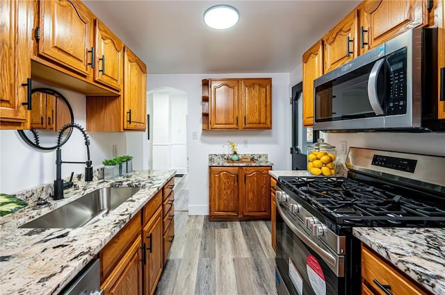 kitchen featuring light hardwood / wood-style floors, light stone countertops, sink, and appliances with stainless steel finishes