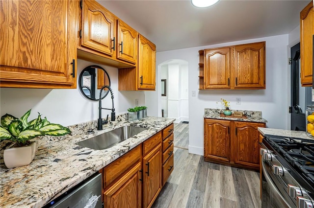 kitchen featuring light stone counters, light wood-type flooring, sink, and appliances with stainless steel finishes