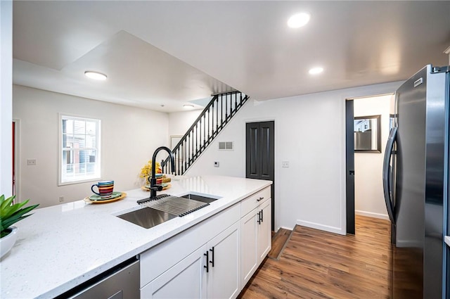 kitchen featuring appliances with stainless steel finishes, dark hardwood / wood-style flooring, light stone counters, sink, and white cabinetry