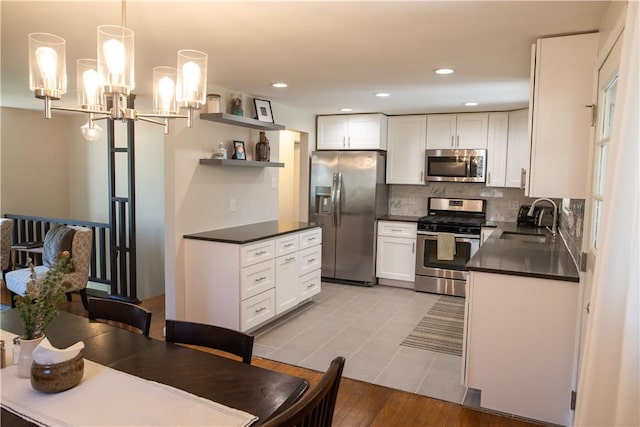 kitchen with white cabinets, decorative light fixtures, sink, and appliances with stainless steel finishes