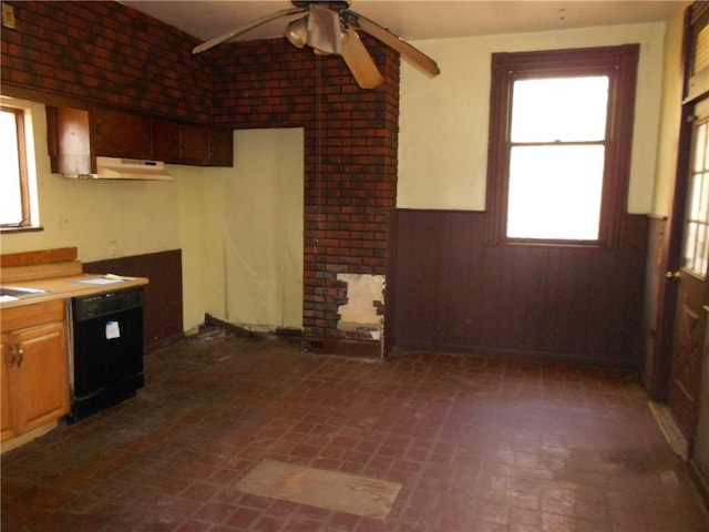 kitchen featuring wood walls, dishwasher, ceiling fan, and brick wall