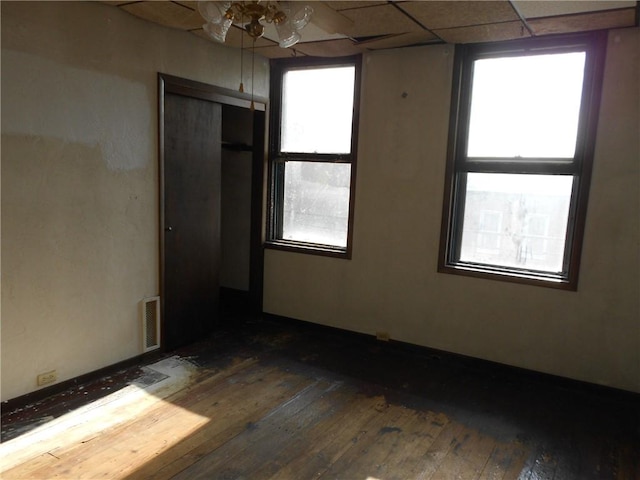 empty room with dark hardwood / wood-style floors, a wealth of natural light, and ceiling fan