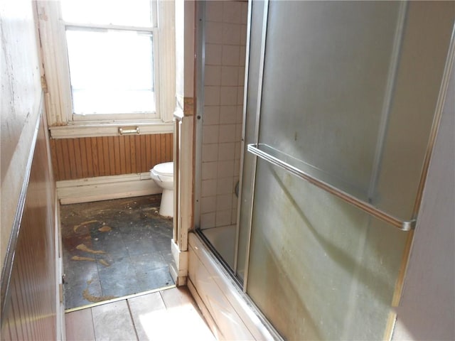 bathroom with toilet and bath / shower combo with glass door