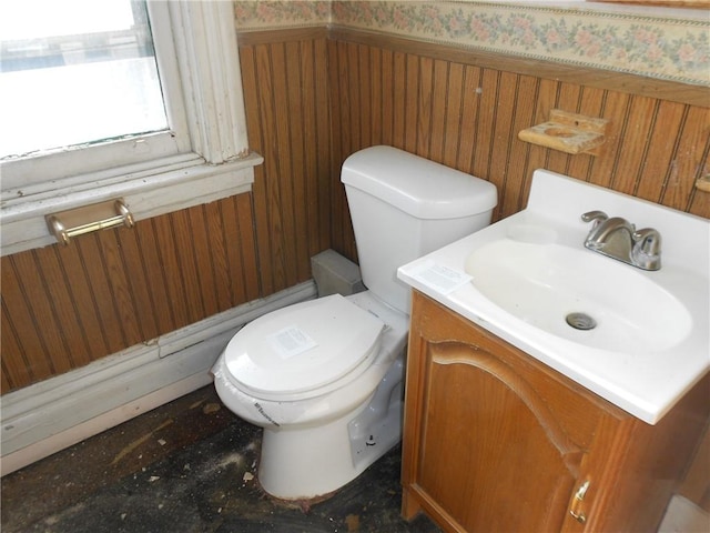 bathroom with vanity, toilet, and wood walls